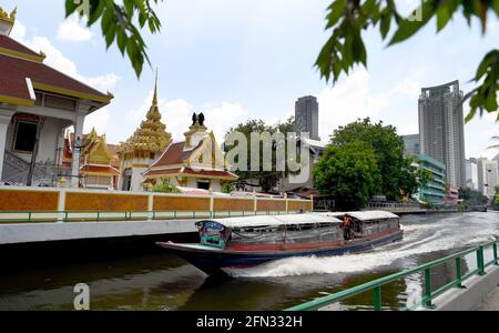 Bangkok, Thailand. Mai 2021. Eine allgemeine Ansicht eines Schnellbootes, das an einem Tempel in einem Kanal vorbeifährt. Die Innenstadt von Bangkok Saen Saep Wasserkanal öffentlichen Verkehrsmitteln bringt Pendler auf einem Kanal (khlong) entlang einer 18 km Strecke mit motorisierten Schnellbooten Service - es hat 27 Pier Haltestellen, 100 Boote mit 40-50 Sitzplätzen, die von 5:30am bis 8:30pm täglich. Kredit: SOPA Images Limited/Alamy Live Nachrichten Stockfoto
