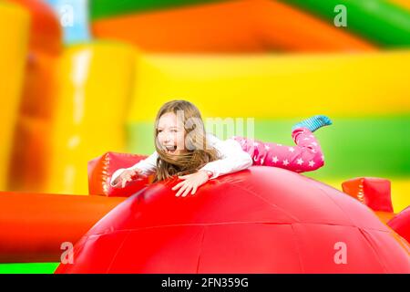 Glückliches kleines Mädchen mit viel Spaß auf einem aufgeblasen Burg beim Springen. Farbenfroher Spielplatz. Stockfoto
