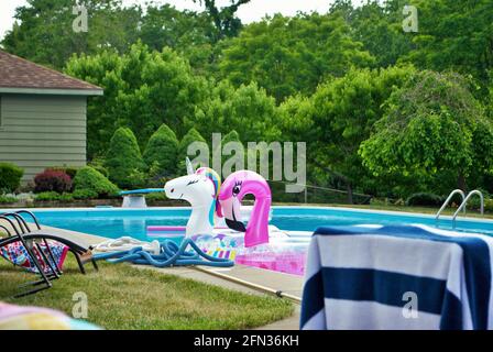 einhorn und rosa Flamingo aufblasbar schwimmend in einem Hinterhof schwimmen Pool Stockfoto