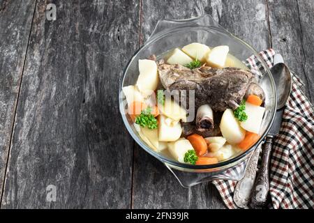 Lammkeule mit Gemüse im Glastopf Holztisch Stockfoto
