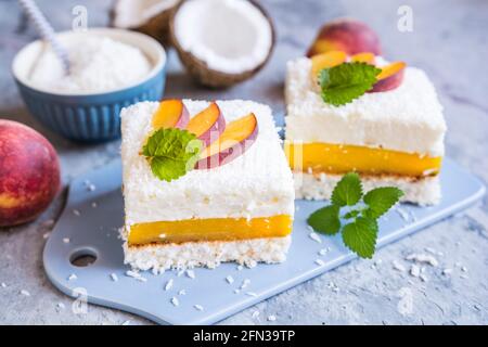 Erfrischendes Kokosnussdessert mit Pfirsichfüllung, gekrönt mit frischen Fruchtscheiben Stockfoto