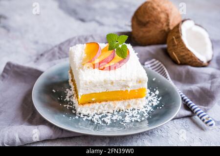 Erfrischendes Kokosnussdessert mit Pfirsichfüllung, gekrönt mit frischen Fruchtscheiben Stockfoto