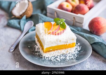 Erfrischendes Kokosnussdessert mit Pfirsichfüllung, gekrönt mit frischen Fruchtscheiben Stockfoto