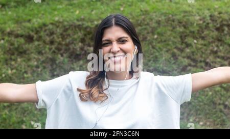 Lateinische Frau, die die Kamera mit weit geöffneten Armen anschaut Stockfoto