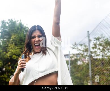 Hispanische Frau, die im Freien Musik hört Stockfoto