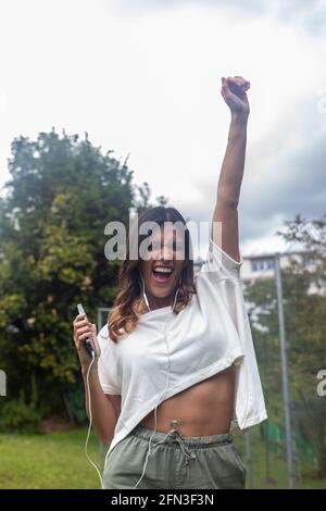 Vertikale Aufnahme einer hispanischen Frau, die im Freien Musik hört Stockfoto