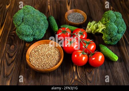 Frisches Gemüse und trockener Buchweizen auf einem Holztisch. Produkte aus biologischem Anbau. Brokkoli, Tomaten, Gurken vom Markt. Richtiges Ernährungskonzept. H Stockfoto