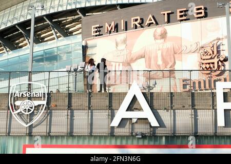 Zwei Personen stehen vor dem Emirates-Fußballstadion, in dem der Arsenal-Fußballverein in Highbury, London, beheimatet ist. Stockfoto