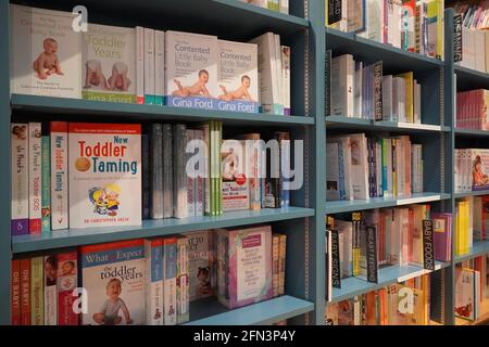 Bücherregal In Der Bibliothek Mit Vielen Kinderbüchern Zum Verkauf. Reiseführer für Eltern, Kleinkinder. Kinderbücher. Bücher Für Kleinkinder. Was Sie erwarten, wenn Sie exp Stockfoto