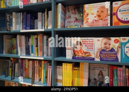 Bücherregal In Der Bibliothek Mit Vielen Kinderbüchern Zum Verkauf. Reiseführer für Eltern, Kleinkinder. Kinderbücher. Bücher Für Kleinkinder. Was Sie erwarten, wenn Sie exp Stockfoto