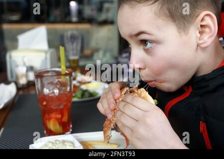 Boy hat Burger auf der Restaurantterrasse im Frühjahr Stockfoto