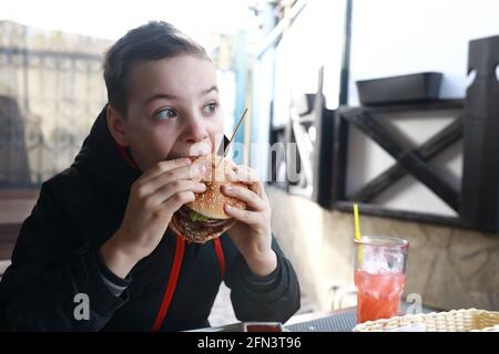 Kinder essen im Frühling Burger auf der Restaurantterrasse Stockfoto