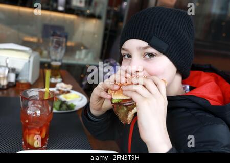 Kinder essen Burger auf der Restaurantterrasse im Frühling Stockfoto