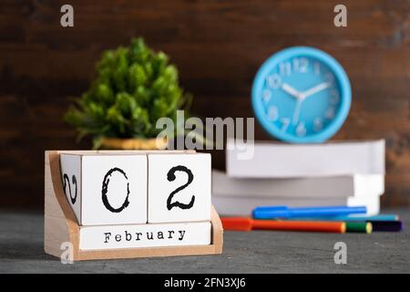 Februar. Februar 02 Holzwürfelkalender mit unscharfen Objekten auf dem Hintergrund. Stockfoto