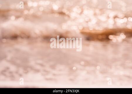 Abstrakte Natur Sommer oder Frühling Meer Meer Hintergrund. Kleine Wellen auf der goldenen, warmen Wasseroberfläche verwischen sich in Bewegung mit Bokeh-Lichtern vom Sonnenuntergang. Urlaub Stockfoto