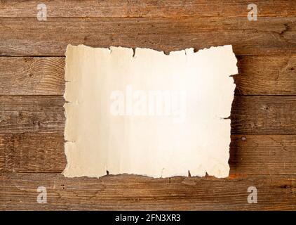 Leeres Blatt vergilbten alten Papyrus mit leerem Platz für Inschrift auf rauem Holzhintergrund Stockfoto