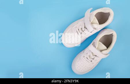 Sneakers aus weißem Leder isoliert auf blauem Hintergrund. Stockfoto