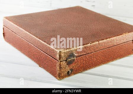 Vintage braun Leder Vinyl Schallplattenbox auf weißem Holzhintergrund. Stockfoto