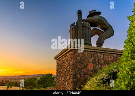 Traubenbrecher-Statue und Landschaft mit Hügeln und Tälern bei Sonnenuntergang am südlichen Eingang zum Napa Valley, Kalifornien, USA Stockfoto