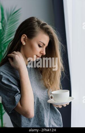 Junge Frau, die zu Hause in der Lounge sitzend studiert Der Boden lehnte sich an ein Sofa und arbeitete mit Laptop und Buchen Stockfoto
