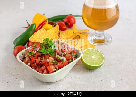 Pico de gallo oder Salsa fresca, traditionelle mexikanische Sauce, aus Tomaten, Zwiebeln, serrano-Pfeffer, Limettensaft, Koriander und Salz mit einem Glas Bier Stockfoto