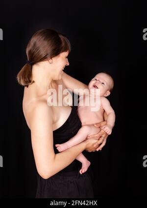 Junge Frau mit niedlichem Neugeborenen im Studio. Lächelnde, liebevolle Mutter Stockfoto