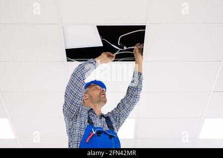 Elektriker installiert LED-Deckenleuchte im Büro Stockfoto