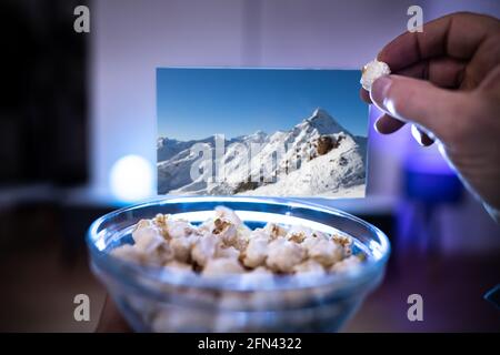 Genießen Sie Popcorn-Snacks beim Fernsehen oder Fernsehen auf dem Sofa Stockfoto