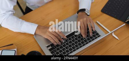 Aufnahme von weiblichen Händen, die auf der Laptop-Tastatur tippen Holztisch im Bürozimmer Stockfoto