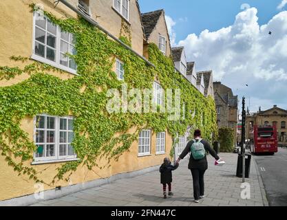 Mutter und Kind gehen an der efeubedeckten Wand des Trinity College der Universität Oxford, England, vorbei. Stockfoto