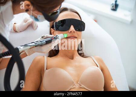 Kosmetikerin, die eine Laserepilation auf dem Gesicht des Patienten durchgeführt hat Stockfoto