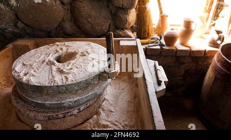 Eine alte Handmühle aus Steinen und Holz. Mehlschleifvorrichtung. Authentisches Kunsthandwerk Stockfoto