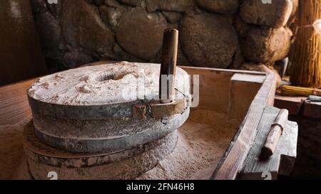 Eine alte Handmühle aus Steinen und Holz. Mehlschleifvorrichtung. Authentisches Kunsthandwerk Stockfoto