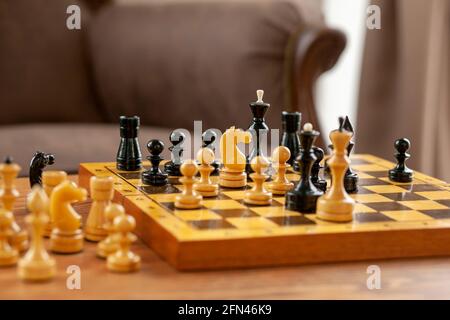 Ein Schachspiel ist ein Pferd, das auf einem Schachbrett steht. Holzschachbrett auf Vintage-Tisch, selektiver Fokus. Stockfoto