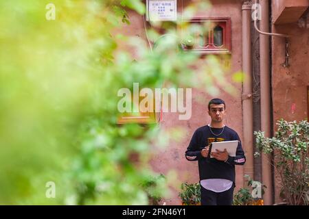 (210514) -- KASHGAR, 14. Mai 2021 (Xinhua) -- Mamattursunjian Mamatimen malt in einer Gasse in der alten Stadt Kashgar in der Autonomen Region Xinjiang Uygur im Nordwesten Chinas, 6. Mai 2021. Die dominante Farbe der Wohnungen in der antiken Stadt Kashgar in Xinjiang ist tiefgelb. Aber in den Werken des 26-jährigen lokalen Malers Mamattursunjian Mamatimen werden mehr Farben wie Orange, Weiß, Lila, Blau verwendet, um die Stadt zu malen. Das ist sein Lebensgefühl und auch ein Gefühl, das die Jugendlichen in Kashgar teilen, sagte Mamattursunjian. „Es braucht Mut, die Tradition zu durchbrechen.“ Mamattursunjian Stockfoto