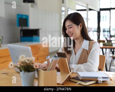 Portrait of female college student doing home work with laptop and books in cafe Stockfoto