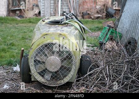 Alte landwirtschaftliche Werkzeuge, die im Garten stehen gelassen wurden. Defekter landwirtschaftlicher Zerstäuber. Ländlicher Lebensstil. Stockfoto