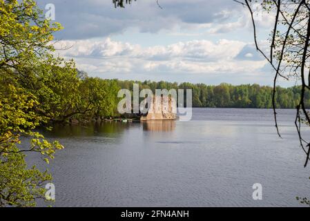 Landschaft auf die alte Burg. Burgruinen am Fluss neben einem Wald mit grünen Bäumen. Wolkiger Sommertag. Stockfoto