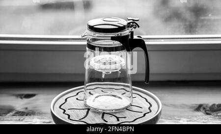 Teekannen aus Kunststoff-Glas mit Knopf und Teeflasche. Stockfoto