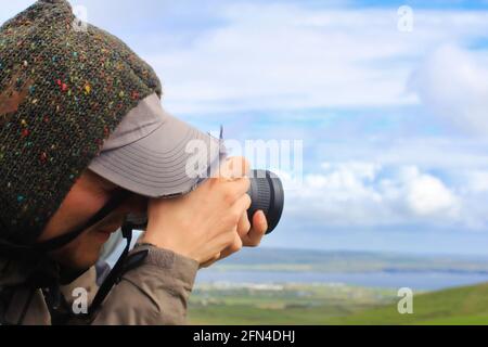 Junger Fotograf macht ein Panoramafoto. Nahaufnahme eines Mannes mit einer Fotokamera. Phorographie in einem Nationalpark. Stockfoto