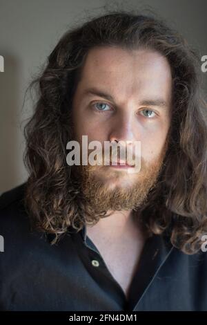 Mann mit grauen Augen, Bart und langen braunen Haaren. Porträt eines jungen Models mit ernstem Ausdruck. Metalhead und viking Life Style. Stockfoto