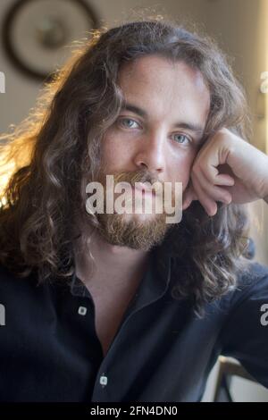 Mann mit grauen Augen, Bart und langen braunen Haaren. Porträt eines jungen Models mit ernstem Ausdruck. Metalhead und viking Life Style. Stockfoto