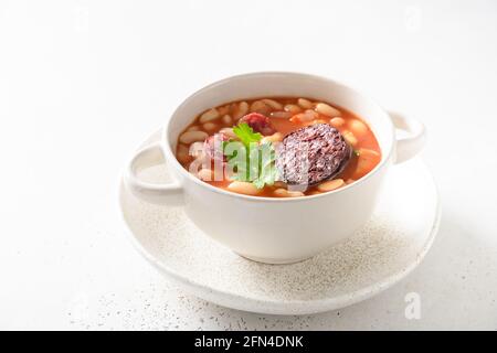 Traditionelle spanische Fabada mit Haricot, Morcilla, Chorizo auf weißem Hintergrund. Nahaufnahme. Asturische Küche Stockfoto