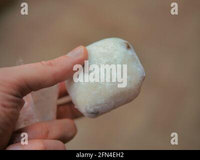 Die Hand hält einen Mame Daifuku Mochi, der auf der Straße gegessen wird. Traditionelles japanisches Reisdessert mit Sesambohnen. Süßes Gebäck mit Füllung. Stockfoto