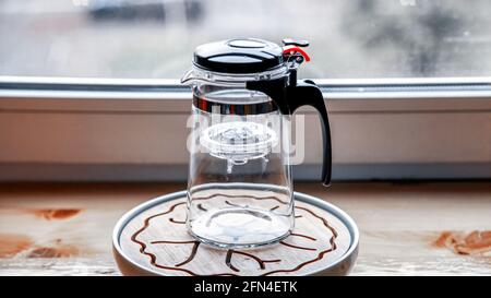 Teekannen aus Kunststoff-Glas mit Knopf und Teeflasche. Stockfoto