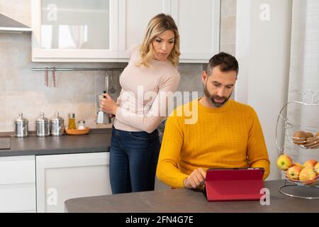 Verdächtige Frau findet ihren Mann entdeckt etwas Schlechtes.. Intrigierte Frau in der Küche bereitet Kaffee hinter ihrem betrügenden Ehemann zu. Stockfoto