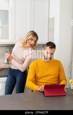 Verdächtige Frau findet ihren Mann entdeckt etwas Schlechtes.. Intrigierte Frau in der Küche bereitet Kaffee hinter ihrem betrügenden Ehemann zu. Stockfoto