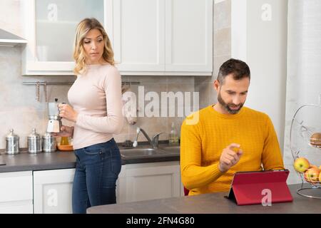 Verdächtige Frau findet ihren Mann entdeckt etwas Schlechtes.. Intrigierte Frau in der Küche bereitet Kaffee hinter ihrem betrügenden Ehemann zu. Stockfoto