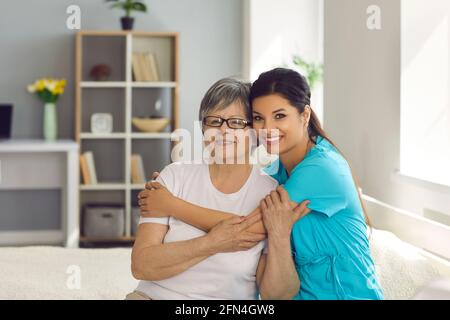 Glückliche ältere Frau zusammen mit ihrer Hauskrankenschwester oder pflegekraft lächelt vor der Kamera Stockfoto