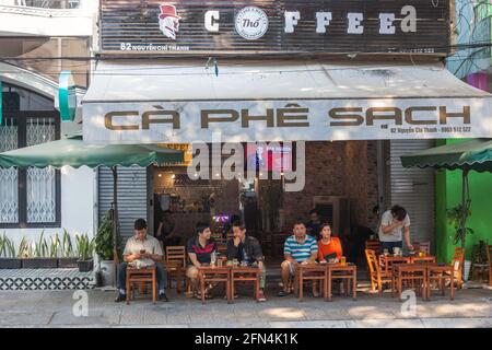 Vietnamesische Freunde sitzen im Freien vor dem Café Ca Phe Sach, Da Nang, Vietnam Stockfoto